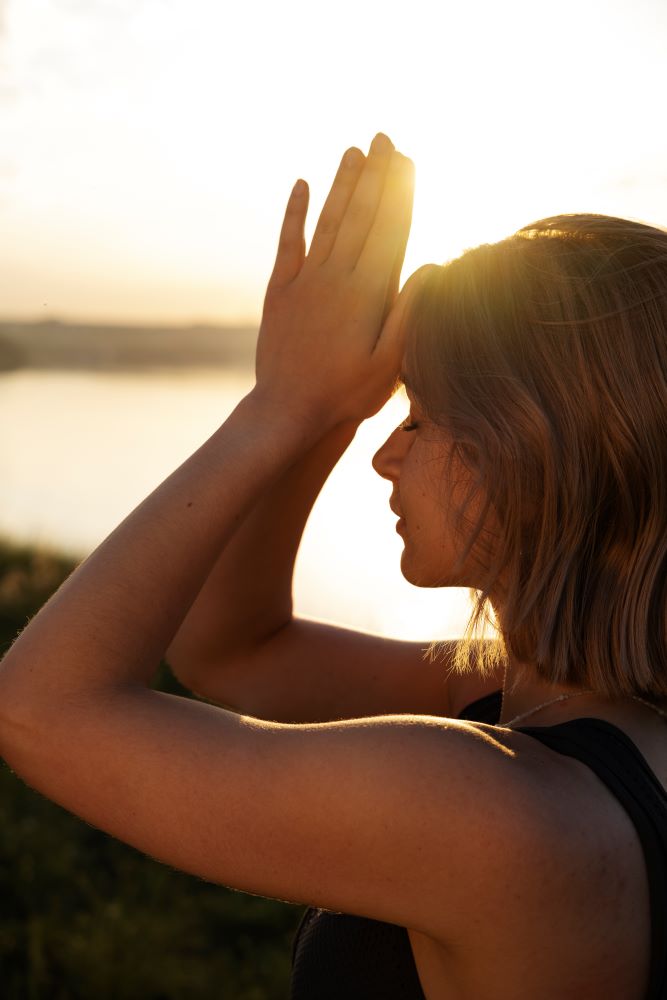 Sophrologie, femme qui fait le signe de namasté, elle est dans la concentration pour se préparer un évènement. elle inspire la sérénité et la confiance.