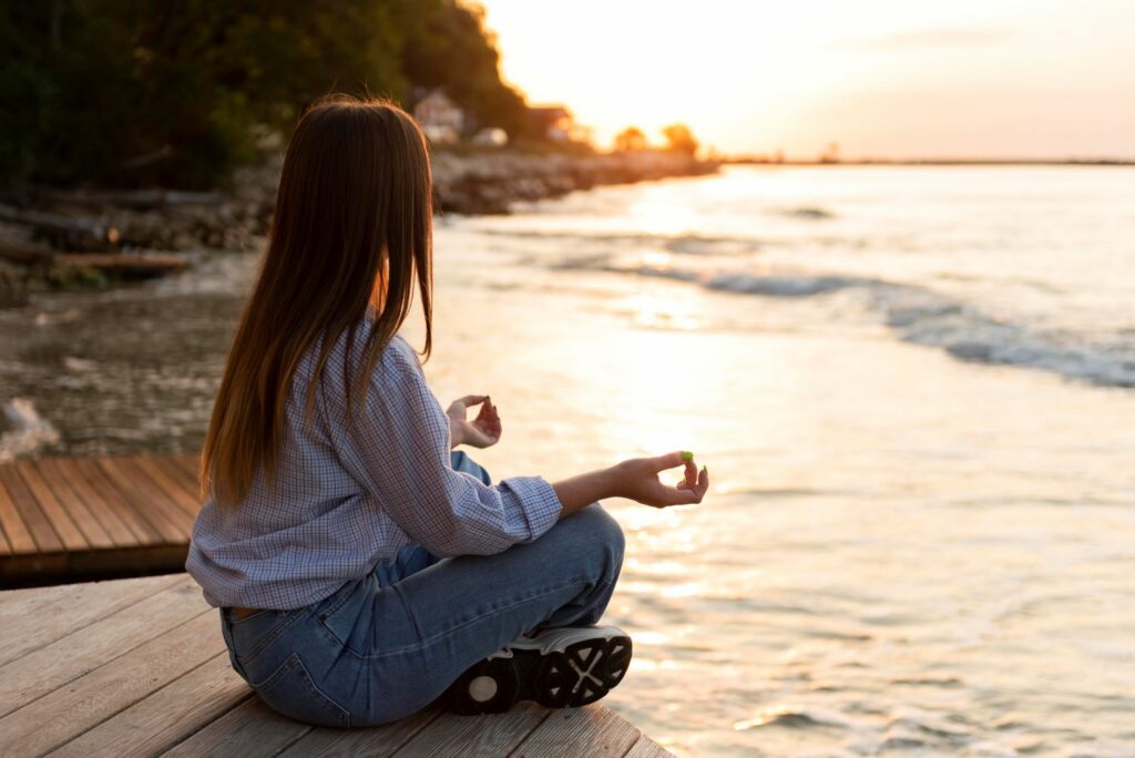 femme qui médite en bord de mer et qui inspire la sérénité et le recentrage intérieur