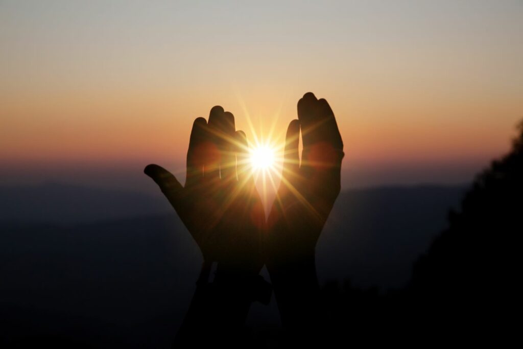 deux mains ouverte laissant passer la lumière du soleil a travers, symbole d'énergie