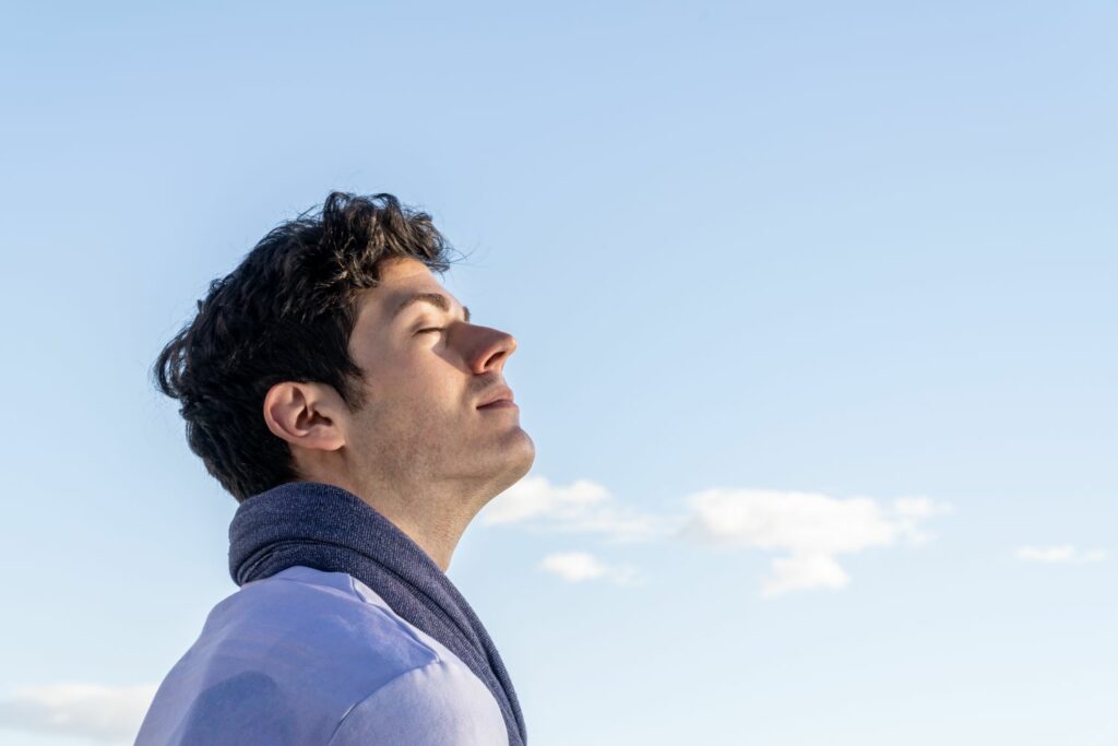 homme avec les yeux fermés respirant le bien être, et la sérénité