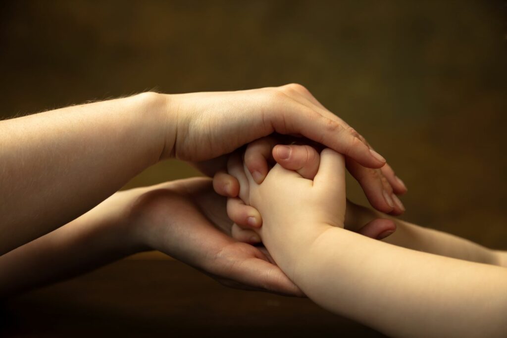 Gros plan sur les mains d'une femme et d'un enfant, figure attachement sécure