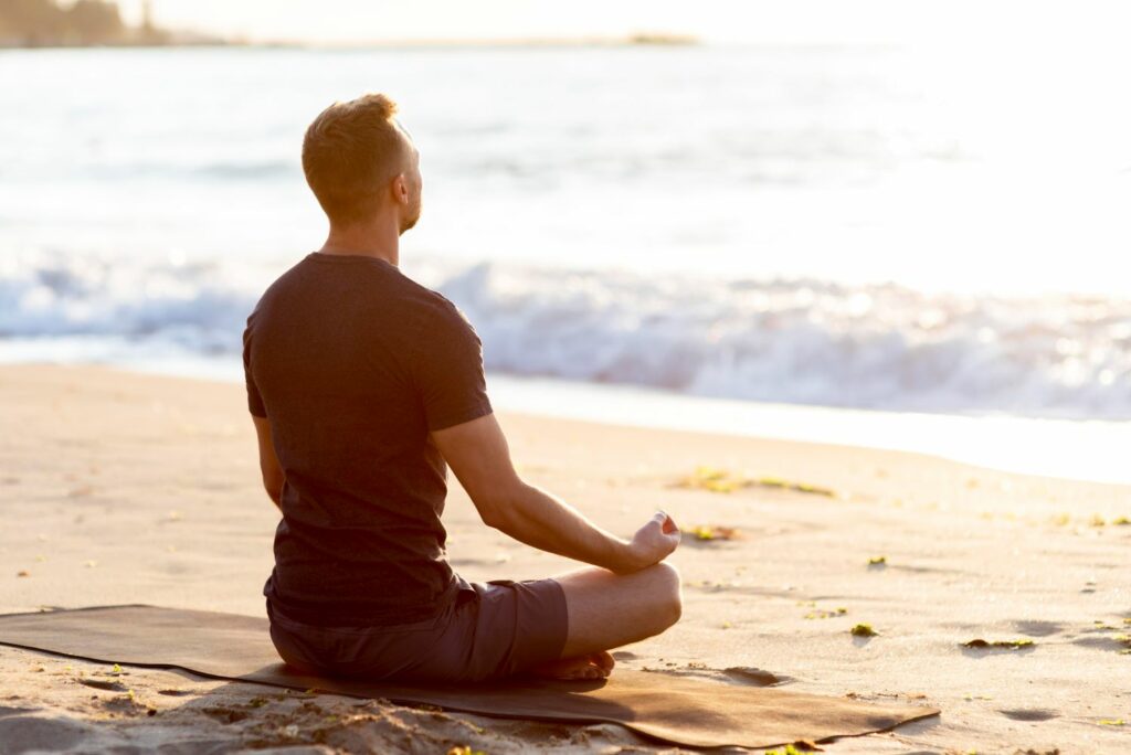 homme en position de méditation face a la mer