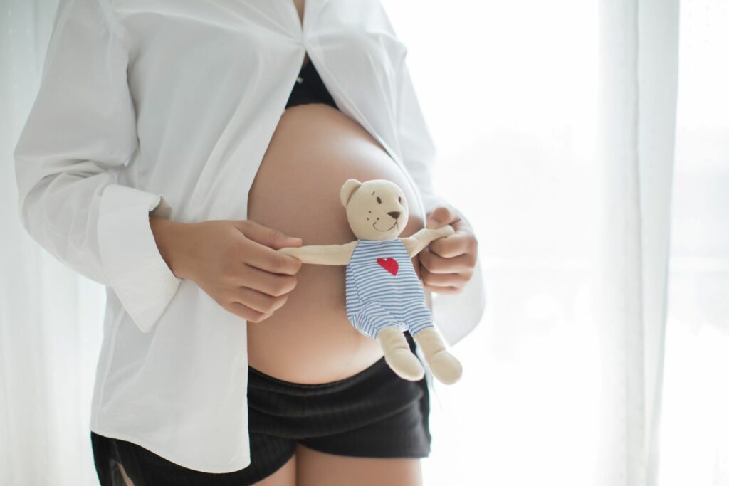 femme enceinte tenant une peluche sur son ventre