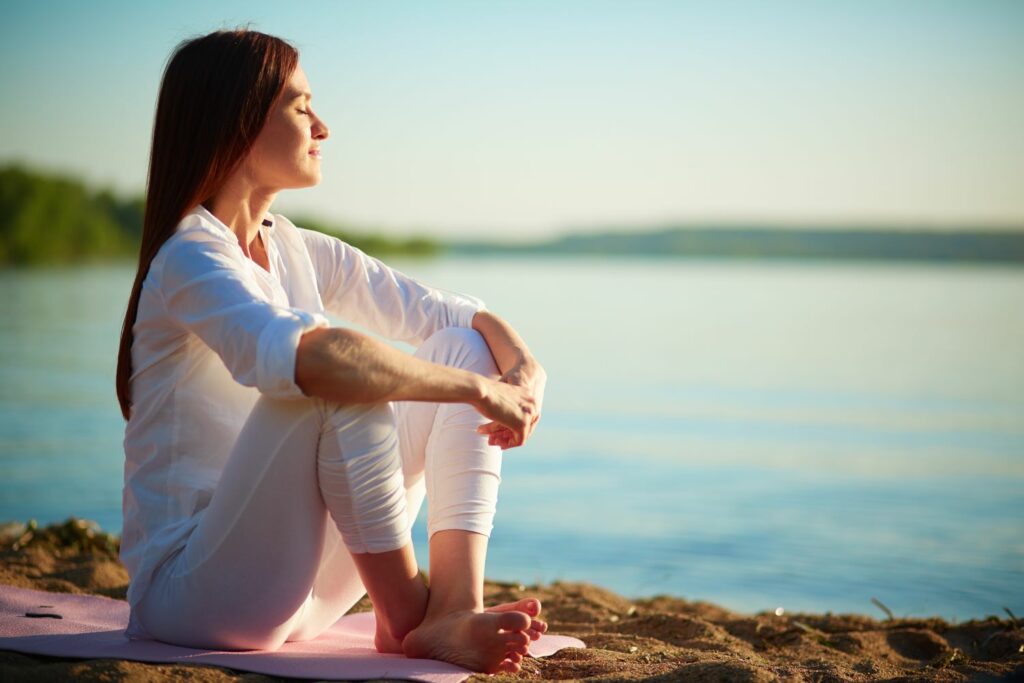 femme assise en bord de mer fermant les yeux et appréciant son bien être. rencontre avec son âme