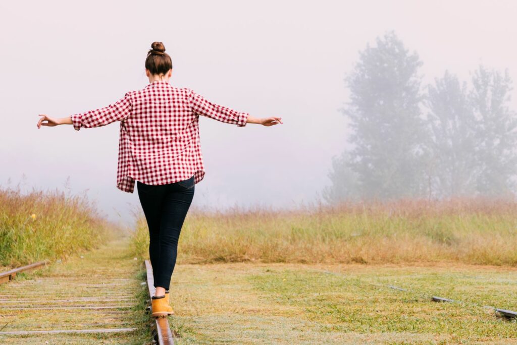 jeune femme en équilibre sur une rail en pleine nature synonyme d'équilibre de vie