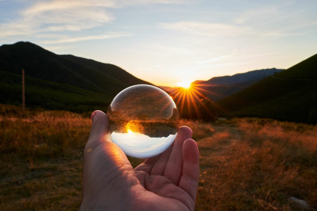 main d'une personne tenant une boule cristal avec rayon de soleil synonyme d'intuition