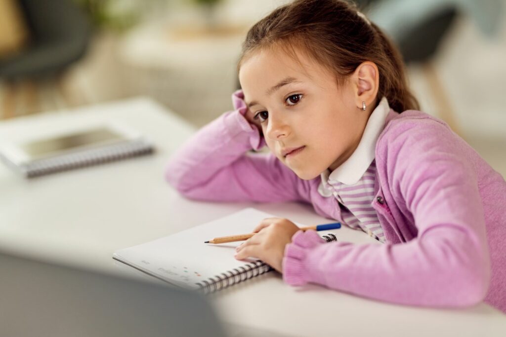 petite fille assise en classe en plein dans ses pensées difficulté de concentration