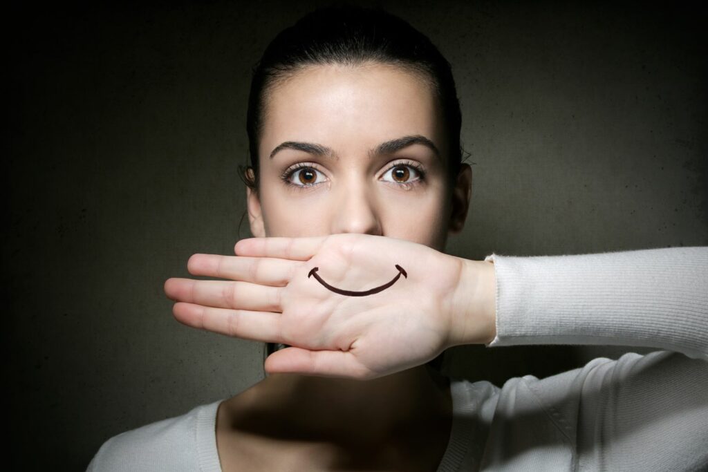 portrait d'une femme montrant une main avec un sourire et une larme a l'oeil montrant les émotions sur le corps