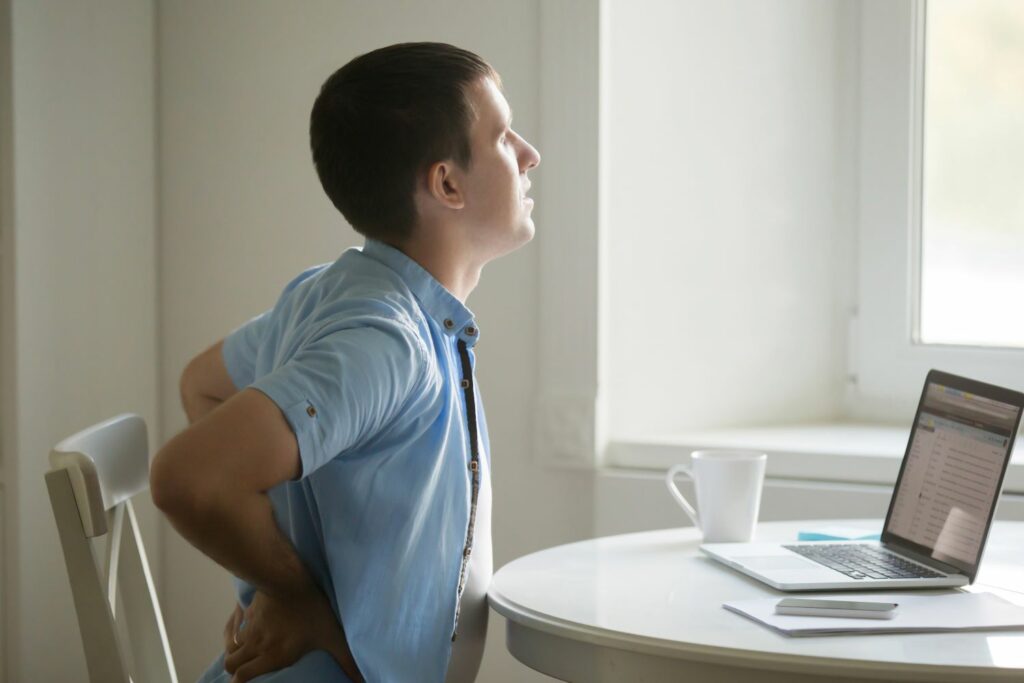 homme assis a son bureau soufrant de maux de dos