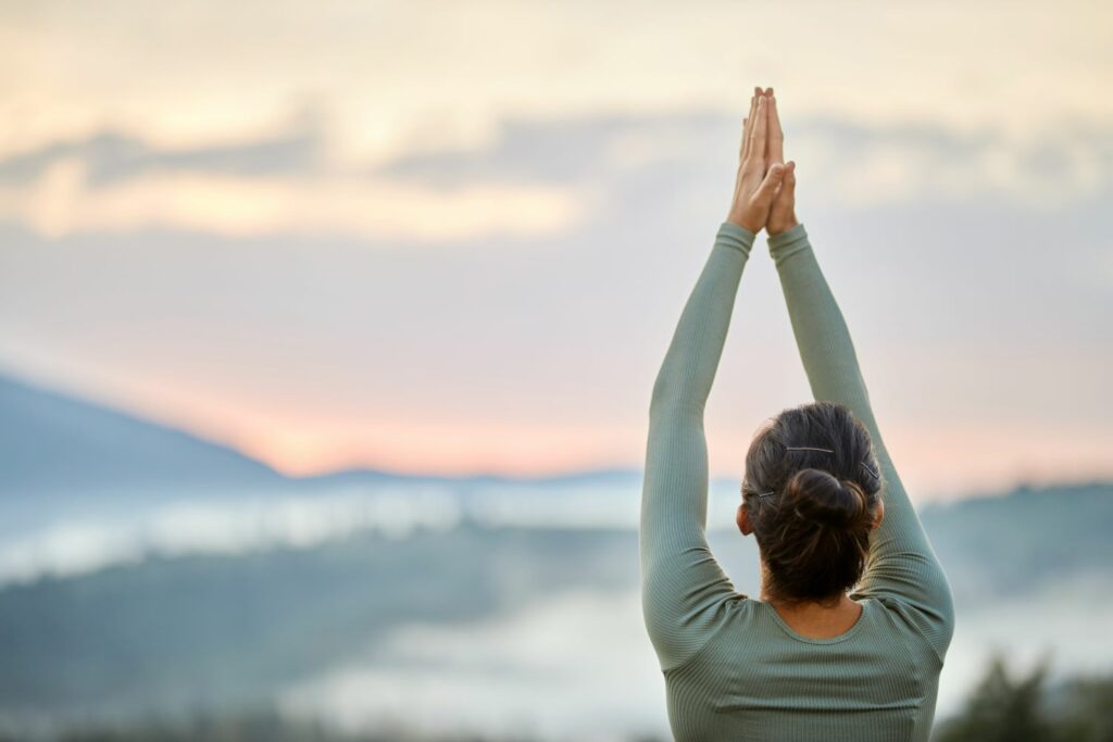 femme en position de gratitude face paysage afin de montrer l'intelligence émotionnel grâce a la sophrologie