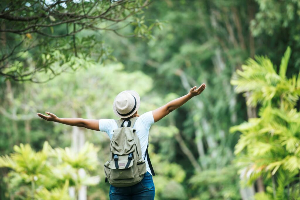 femme levant les bras face a la forêt signe de vitalité grâce à la sophrologie