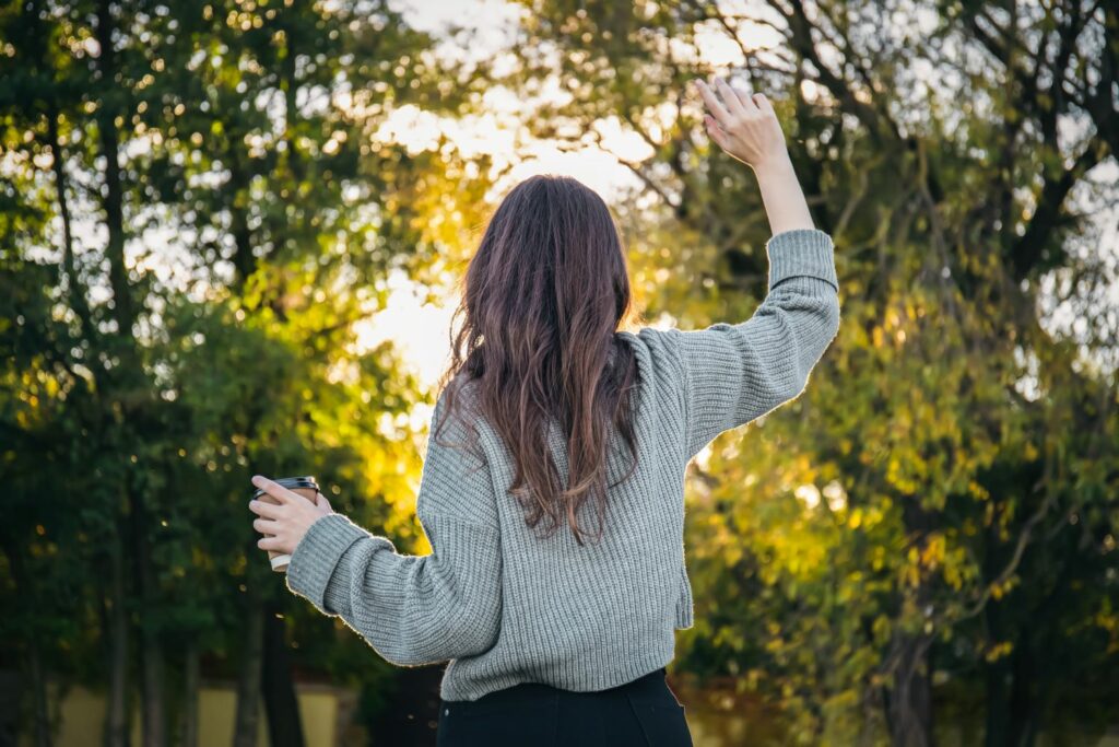 jeune femme vu de dos levant les bras inspirant la confiance en soi