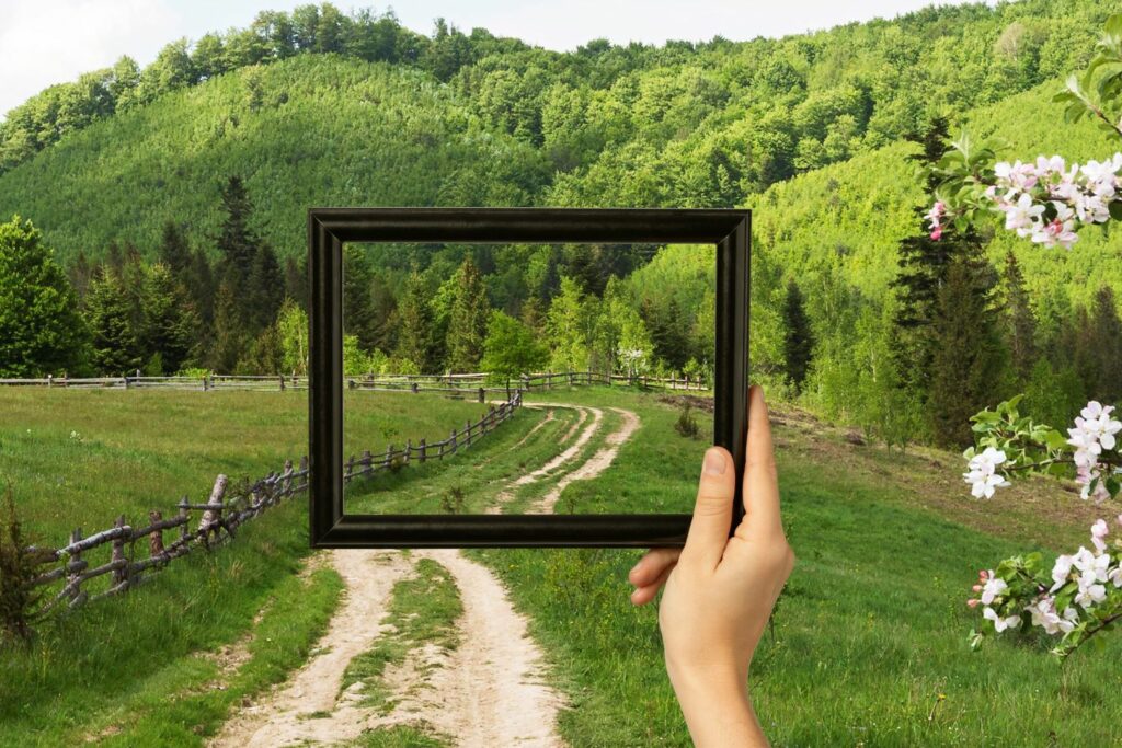 paysage naturel avec une personne tenant un cadre sans toile capturant l'instant présent de sa balade