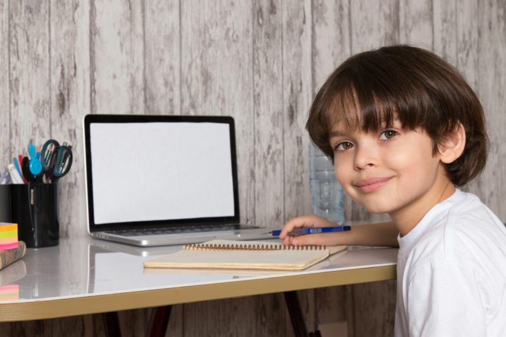 enfant souriant qui apprend a taper a l'ordinateur grâce au séance d'ergothérapie