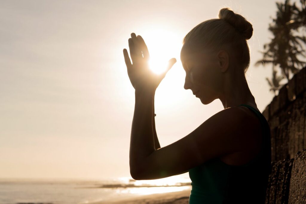 jeune femme méditant au coucher de soleil